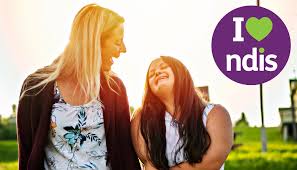 People smiling beside an I love NDIS sign